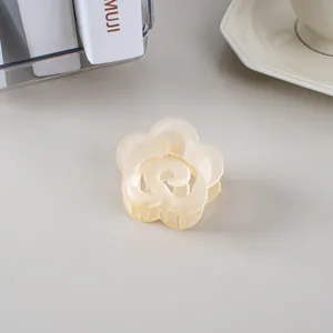 Détail d'une pince à cheveux fleurie crème mate dans un décor de bureau minimaliste