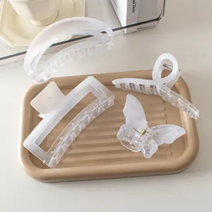 Detail of four matte translucent white hair claws on a tray in a lifestyle setting