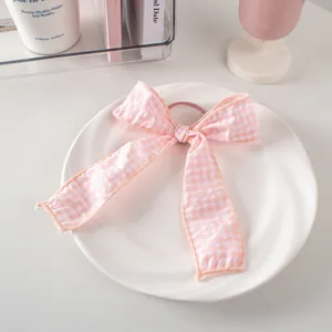 Fiocco per capelli a quadretti rosa e bianchi su piatto di ceramica e sfondo sobrio