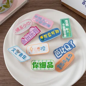 Gros plan de pinces à cheveux en acrylique colorées avec citations sur une assiette