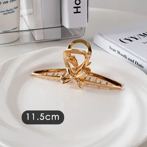 Détail d'une pince à cheveux dorée de 11,5 cm en métal poli avec forme de nœud creux