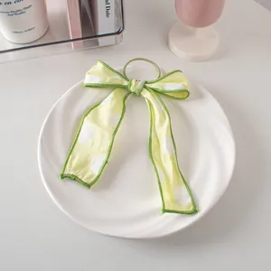 Dettaglio di un elastico per capelli con fiocco verde a pois su un piatto di ceramica bianco