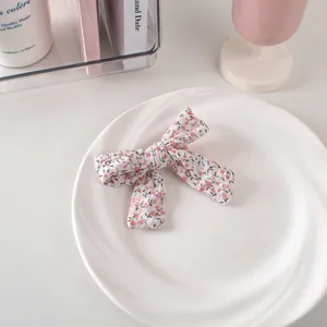 Dettaglio molletta a fiocco in cotone floreale con fiori rosa su piatto di ceramica