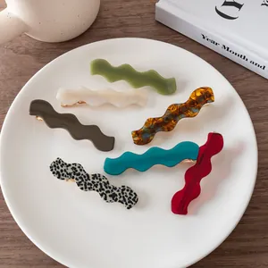 Detail of wavy acetate hair clips in multiple colors on a white ceramic plate