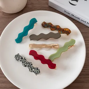 Detailed view of assorted tortoise shell wavy resin hair clips on a white ceramic tray