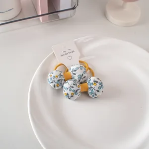 Dettaglio di elastici per capelli con fiocco floreale e bacche blu su carta
