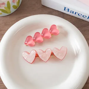 Pink heart hair clip set with translucent jelly and marble patterns on white plate