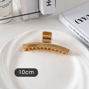 Détail d'une pince à cheveux en métal doré de 10cm au design courbé avec dents solides