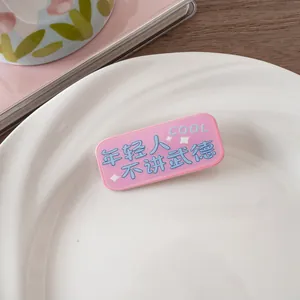 Gros plan d'une pince à cheveux rose en acrylique avec texte bleu et étoiles
