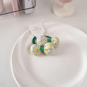 Dettaglio di elastici per capelli floreali con stampe blu e gialle su piatto di ceramica