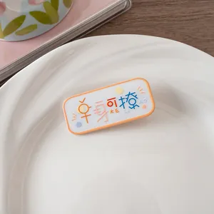 Gros plan d'une jolie pince à cheveux en acrylique avec texte amusant et bordure orange