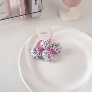 Dettaglio di elastici per capelli in tessuto floreale con lacci rosa e ciondoli a sfera