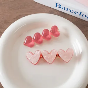 Close-up of heart-shaped hair clips in translucent pink resin and marble acetate texture