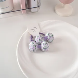 Dettaglio di elastici per capelli con fiocco floreale viola su vassoio bianco