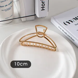 Détail d'une pince à cheveux en métal doré de 10 cm avec design ajouré sur assiette