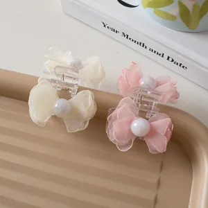 Detail of elegant mesh bow hair claw clips with large iridescent pearls in pink and beige