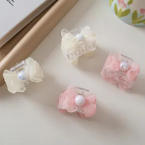 Close-up of four small pearl mesh bow hair clips in beige and pink for elegant hair styling