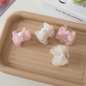 Detailed set of four small pearl mesh bow hair claws in pink and cream on a tray