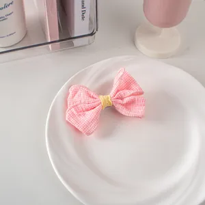 Dettaglio di un fermaglio per capelli a fiocco a quadretti rosa con pizzo giallo su piatto