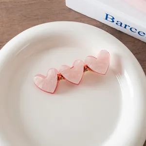 Detailed macro view of triple pink marble-textured acetate hearts on a gold hair clip