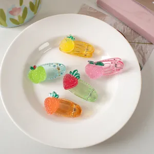 Detail shot of five glittery fruit-shaped hair clips in a white ceramic dish