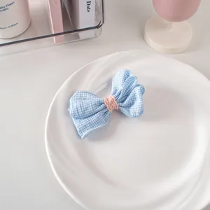 Dettaglio di un fermaglio per capelli a fiocco a quadretti blu e bianchi con maglia rosa
