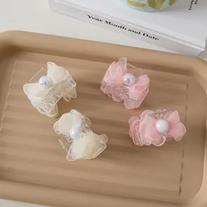Detail of four mini hair clips with mesh bows and pearls in cream and pink tones