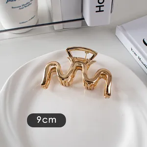Vue détaillée d'une pince à cheveux ondulée en métal doré de 9cm avec fini poli