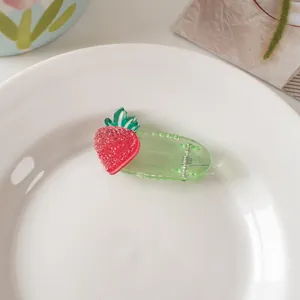 Detail of green transparent clip with red glitter strawberry decoration for kids