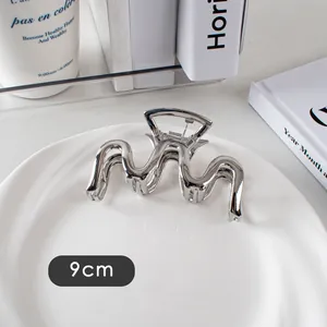 Détail d'une pince à cheveux vague en métal argenté de 9cm sur une assiette blanche
