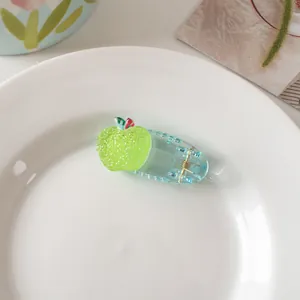Detailed view of a mini light blue transparent hair clip with a green frosted apple design