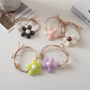 Lot de 5 chouchous fleurs colorées avec perles et breloques sur fond de couleur crème