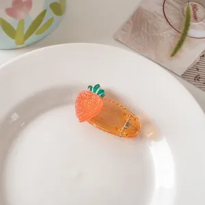 Detail view of a cute orange fruit resin hair clip on a white decorative ceramic plate