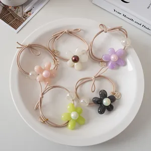 Gros plan de cinq élastiques à fleurs colorés avec perles sur une assiette en céramique