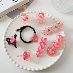 Détail d'un ensemble de pinces à cheveux coeur rose et élastique sur une assiette blanche