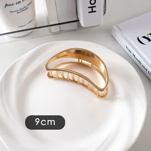 Détail de la grande pince à cheveux en métal doré de 9 cm sur assiette élégante