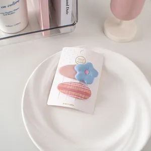 Dettaglio di due fermagli per capelli a fiori e a quadretti su scheda display