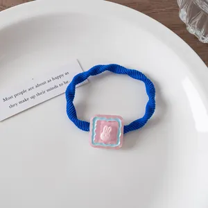 Detail eines blauen Spiral-Haargummis mit einem süßen rosa 3D-Hasen-Anhänger aus Harz