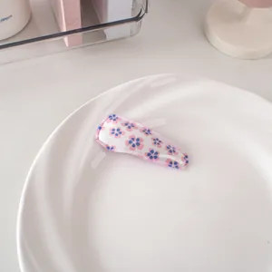 Dettaglio di un fermaglio BB in tessuto con motivi floreali rosa e blu su base bianca