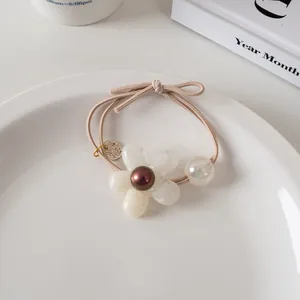 Détail d'un élastique à cheveux fleur en résine blanche et perle colorée sur assiette