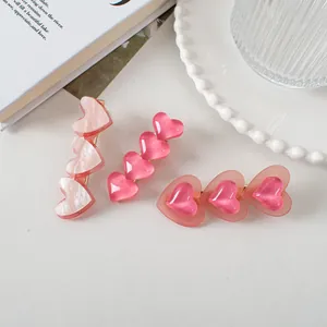 Détail de trois pinces à cheveux en forme de cœur rose, style marbre et résine