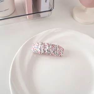 Dettaglio del fermaglio per capelli in tessuto arricciato con motivo floreale rosa