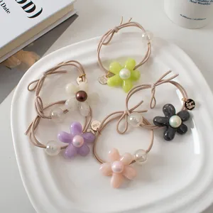 Détail de 5 chouchous fleurs avec perles présentés dans un plat en céramique blanc