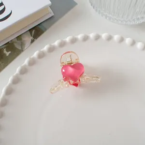 Gros plan d'une pince à cheveux rose translucide en forme de cœur sur une assiette blanche