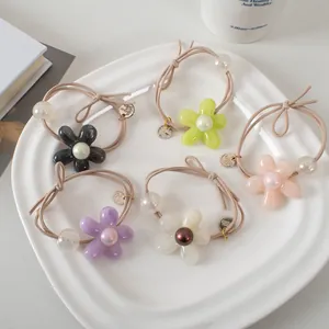 Lot de 5 élastiques à cheveux avec fleurs en gelée et perles sur un plateau blanc
