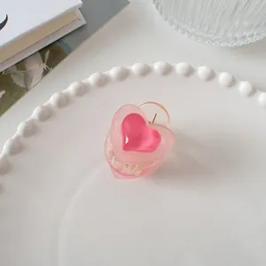 Détail d'une pince à cheveux double cœur rose translucide sur une assiette blanche