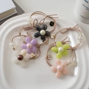 Gros plan de cinq élastiques à fleurs en résine avec perles sur plateau blanc