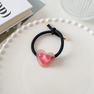 Détail d'un élastique à cheveux cœur rose avec effet œil de chat sur assiette blanche