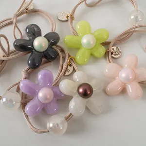 Détail de cinq chouchous fleurs colorés en résine avec perles nacrées et élastiques