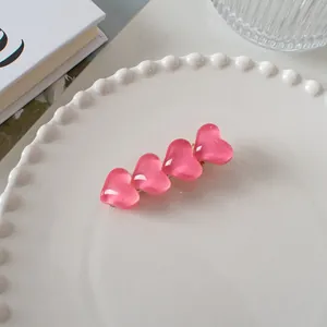 Détail d'une pince à cheveux en forme de cœur rose sur un plateau décoratif blanc